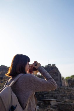 Blogu ve sosyal medyası için sırt çantalı şık bir turist. İsrail 'de antik taş kalıntıları yakınında bir turist. Beit She'an. Kameralı bir kız..