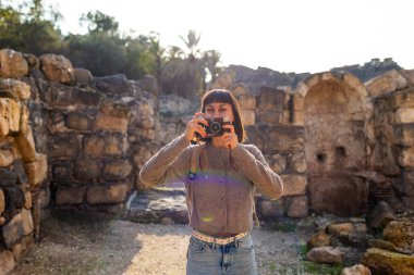 Blogu ve sosyal medyası için sırt çantalı şık bir turist. İsrail 'de antik taş kalıntıları yakınında bir turist. Beit She'an. Kameralı bir kız..