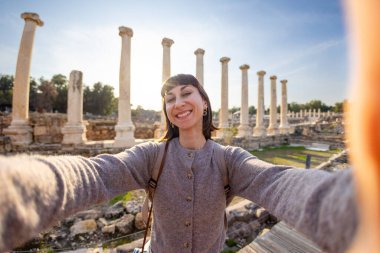 Bir turist köşe yazılarına ve arkeolojik sitelere selfie çeker. Fotoğraf alçak bir açıdan çekilmiş. Sosyal medya için içerik oluşturur. İsrail 'i geziyorum, Beit She' an.