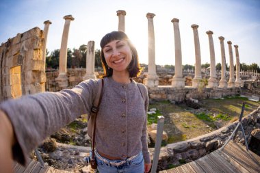 Bir turist köşe yazılarına ve arkeolojik sitelere selfie çeker. Fotoğraf alçak bir açıdan çekilmiş. Sosyal medya için içerik oluşturur. İsrail 'i geziyorum, Beit She' an.