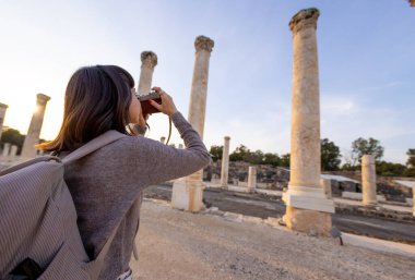 Blogu ve sosyal medyası için sırt çantalı şık bir turist. İsrail 'de antik taş kalıntıları yakınında bir turist. Beit She'an. Kameralı bir kız..