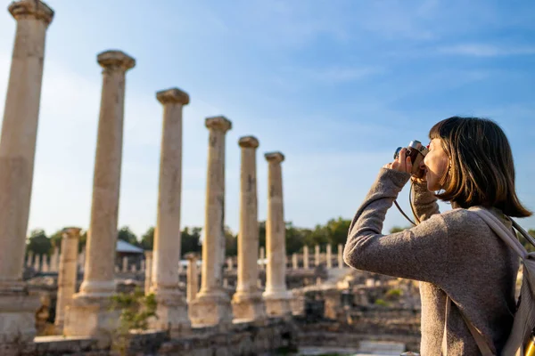 Sırt çantası ve fotoğraf makinesi olan genç bir kadın antik harabeleri keşfediyor. Kadın seyahat blogları, kültür ve turizm hakkında belgeseller için videolar çekiyor. blog için içerik oluşturur. Beit She 'an, İsrail.