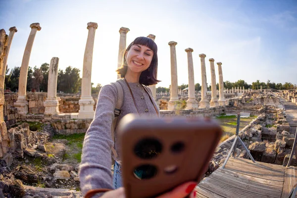Bir turist köşe yazılarına ve arkeolojik sitelere selfie çeker. Fotoğraf alçak bir açıdan çekilmiş. Sosyal medya için içerik oluşturur. İsrail 'i geziyorum, Beit She' an.