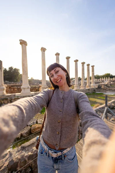 Bir turist köşe yazılarına ve arkeolojik sitelere selfie çeker. Fotoğraf alçak bir açıdan çekilmiş. Sosyal medya için içerik oluşturur. İsrail 'i geziyorum, Beit She' an.