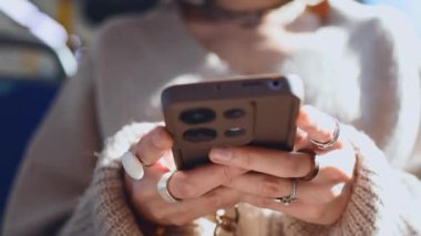 Elinde telefon olan bir otobüs yolcusu. Genç, güzel Avrupalı bir kadın akıllı telefonuyla mesaj atıyor.