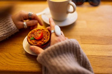Bir kız sıcacık bir kafede kahvaltı yapıyor. Taze hamur işleri. Pastanede yemek..