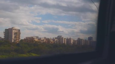 Tren penceresinden bir manzara, gün boyunca bulutlu bir gökyüzünün altında bir şehir manzarası. İsrail 'de seyahat. Hayfa ve Tel Aviv arasındaki tren