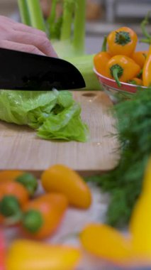 Mutfak tezgahında taze sebze doğrayan bir adam. Kesme tahtasıyla sebze doğrayan ellerin yakın çekimi.