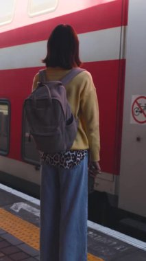 Dikey çekim. Bir yolcu tren bekliyor. Şık bir genç kadın platformda tren bekliyor. Trenle yolculuk.