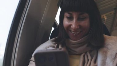 Bir kız akıllı telefon kullanıyor, internette geziniyor ve trende internetten iletişim kuruyor. Kız trendeki bir pencerenin yanında oturuyor.