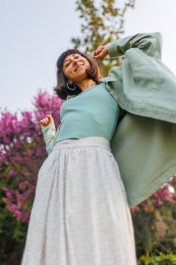 Güzel, gezgin, esmer bir kadının yakın plan portresi. Şapkalı, şık yaz kıyafetleri giyiyor. Yaz tatili boyunca sahilde gülümseyen neşeli genç bir kadın. Mutlu kız.