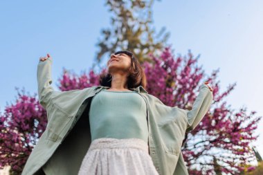Mutlu bir kızın portresi. Genç bir esmer şehirde dururken mutlu bir şekilde gülümsüyor. Gömlekli, şık bir kız. Yaz Portresi