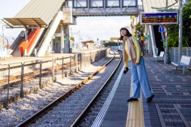 Tren yolcusu. Şık genç bayan etrafına bakıyor ve platformda treni bekliyor. Trenle seyahat et..
