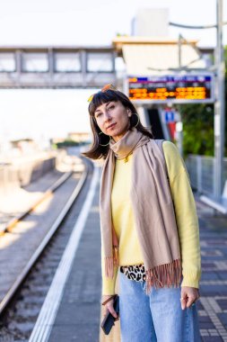 Tren yolcusu. Şık genç bayan etrafına bakıyor ve platformda treni bekliyor. Trenle seyahat et..