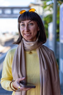 Tren bekleyen genç bir kadın. Telefonundaki uygulamayı kullanarak tren tarifesini kontrol eden bir yolcu. Tren istasyonunda bir kız..