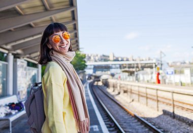 Şık bir kız istasyonda tren bekliyor. İstasyonda piercing takan ve şık güneş gözlüklü bir kızın portresi. Bir toplu taşıma yolcusu.