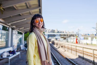 Tren yolcusu. Şık genç bayan etrafına bakıyor ve platformda treni bekliyor. Trenle seyahat et..