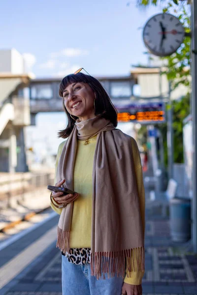 Tren bekleyen genç bir kadın. Telefonundaki uygulamayı kullanarak tren tarifesini kontrol eden bir yolcu. Tren istasyonunda bir kız..