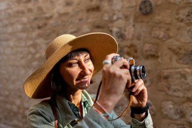 Kameralı kız. Şapkalı ve kameralı şık bir kız Arap şehrinin caddesinde duruyor. Maceralar ve seyahat.