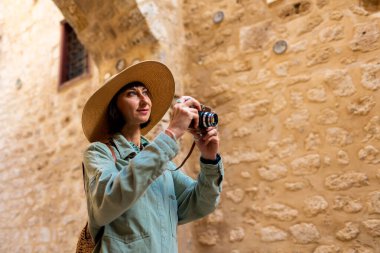 Şapkalı güzel bir kadın dışarıda analog kamera kullanarak fotoğraf çekiyor. Arap ülkelerine gitmek. seyahat ve tatil.