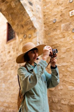 Şapkalı güzel bir kadın dışarıda analog kamera kullanarak fotoğraf çekiyor. Arap ülkelerine gitmek. seyahat ve tatil.