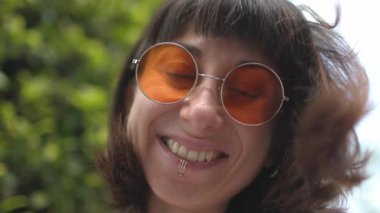 Güneş gözlüklü mutlu bir kadının yüzü. Komik bir şakaya gülen bir insanın gülümsemesi ve duyguları. Kız gülümsüyor..