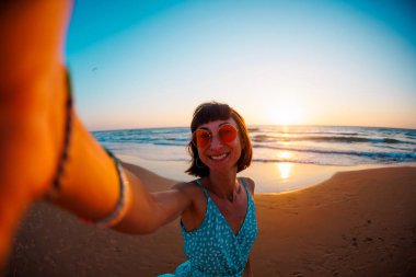 Genç kız sahilde selfie çekiyor. Kız denizin kenarında dinleniyor..