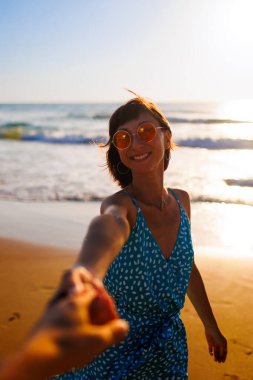 Sahildeki kız. Sahilde çıplak ayaklı, güzel elbiseli bir kız. Elbiseli bir kadın kumlu bir sahilde duruyor ve tatilin tadını çıkarıyor..
