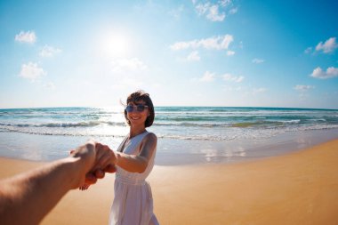 Beni takip edin. Mutlu genç bir kadın arkadaşının elini tutuyor. Birbirlerine aşık çiftler sahilde eğleniyorlar. Elbise giymiş güzel bir kız sahilde yürüyor, erkek arkadaşının elini tutuyor, romantik bir yürüyüş..