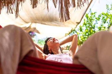 Hamakta yatan kız. Yaz tatilinin tadını çıkaran mutlu genç bir kadın. Romantik tasasız ruh hali konsepti. Yaz havası.