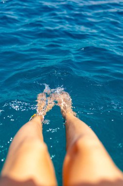 Yaz havası. Suda dinlenen, bronzlaşan, bacaklarını suya sıçratan bir kadının güzel ince bacakları. Dinlenen bir kız..