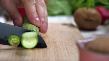 Ahşap bir tahtanın üzerinde keskin bir bıçakla kabak doğrayan bir şef. Vejetaryen yemekleri..