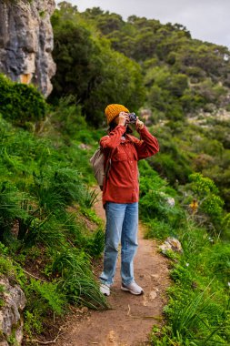 Bir kız fotoğraf çekiyor. Yürüyüş sırasında bir kadın fotoğraf çekiyor. Bir kadın fotoğrafçı sosyal medya için içerik çekiyor. Aktif eğlence ve spor.