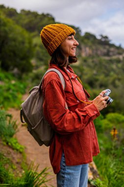 Bir kız fotoğraf çekiyor. Yürüyüş sırasında bir kadın fotoğraf çekiyor. Bir kadın fotoğrafçı sosyal medya için içerik çekiyor. Aktif eğlence ve spor.