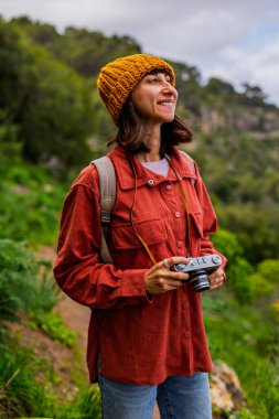 Kameralı bir kız. Bir kadın yürüyüş sırasında doğanın ve dağların fotoğraflarını çekiyor. Bir kadın fotoğrafçı sosyal medya için içerik çekiyor. Aktif eğlence ve spor.