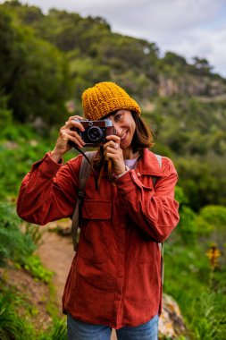 Bir kız fotoğraf çekiyor. Yürüyüş sırasında bir kadın fotoğraf çekiyor. Bir kadın fotoğrafçı sosyal medya için içerik çekiyor. Aktif eğlence ve spor.