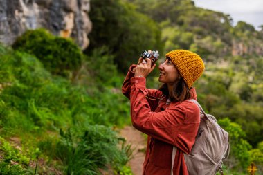 Kameralı bir kız. Bir kadın yürüyüş sırasında doğanın ve dağların fotoğraflarını çekiyor. Bir kadın fotoğrafçı sosyal medya için içerik çekiyor. Aktif eğlence ve spor.