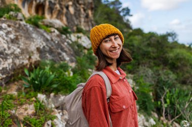 Mutlu bir kızın portresi. Bir kadın dağlarda yürüyüş yapıyor ve eğleniyor. Sırt çantalı bir kadın. Aktif eğlence ve spor.