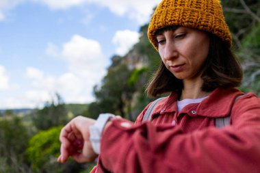 Genç bir kadın akıllı koluna bakar. Ukalalığını kontrol ediyorum. Ormandaki bir kadın yürüyüş sırasında seyrüsefer aracı olarak akıllı kaset kullanıyor. Bir kız saatine bakar..