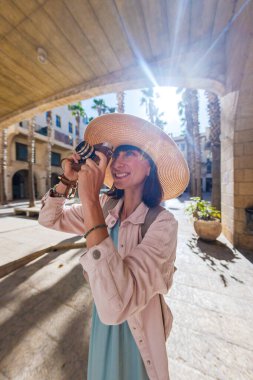 Kameralı kadın fotoğrafçı dışarıda fotoğraf çekiyor. Dışarıdaki kameralı kız. Gezintiler ve şehir yürüyüşleri. Yaşam tarzı, seyahat ve insan kavramı.