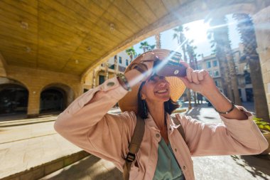 Şehirde fotoğraf çeken bir kadın fotoğrafçı. Genç bayan fotoğrafçı objektife nişan alıyor ve çekim sürecinin tadını çıkarıyor. seyahat ve içerik yaratmak. seyahat ve tatil.