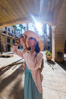 Kameralı kadın fotoğrafçı dışarıda fotoğraf çekiyor. Dışarıdaki kameralı kız. Gezintiler ve şehir yürüyüşleri. Yaşam tarzı, seyahat ve insan kavramı.
