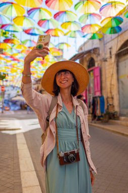 Kadın gezgin, tarihi bir şehirde telefonuyla tarihi işaretlerin fotoğraflarını çekiyor. gökyüzü şemsiyesi Kız içerik yaratır.