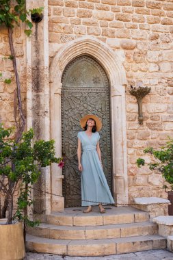 Kız tatilden ve şehirde gezmekten zevk alıyor. Eski Jaffa şehrinde güzel caddelerde yürüyen elbiseli genç bir kadın. İsrail. seyahat ve macera.