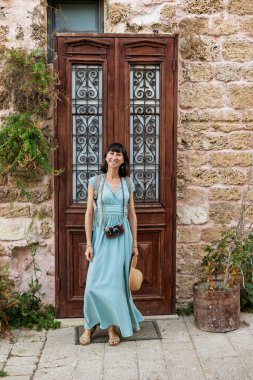 Kız tatilden ve şehirde gezmekten zevk alıyor. Eski Jaffa şehrinde güzel caddelerde yürüyen elbiseli genç bir kadın. İsrail. seyahat ve macera.