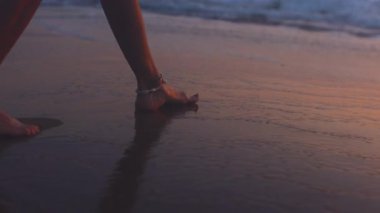 Sahilde bir kız. Sahilde çıplak ayaklı bir kadının yakın çekimi. Bir kadın sahilde yürüyor ve yavaşça denize giriyor.