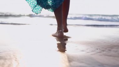 Sahilde bir kız. Sahilde çıplak ayaklı bir kadının yakın çekimi. Bir kadın sahilde yürüyor ve yavaşça denize giriyor.