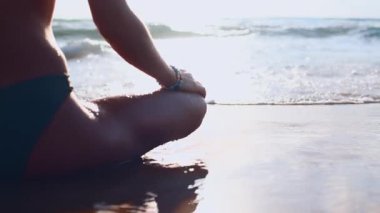 Sahilde meditasyon. Bir kız suyun yakınındaki kumda oturuyor, sakince denize bakıyor. Sahildeki kız. Meditasyon, sakinlik