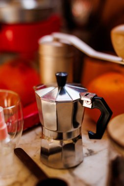 Kahve yapmak için gerekli malzemeler. Moka demliği, fasulye spreyi, kahve değirmeni ve kahve çekirdekleri mutfak masasında duruyor. Kahve yapma konsepti.