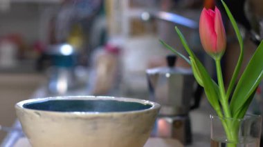 Mutfak masasında, çiçeğin yanında bir kase sıcak kahvaltı. Sıcak mutfak ve sağlıklı yemek kavramı. Evde yemek yemek..